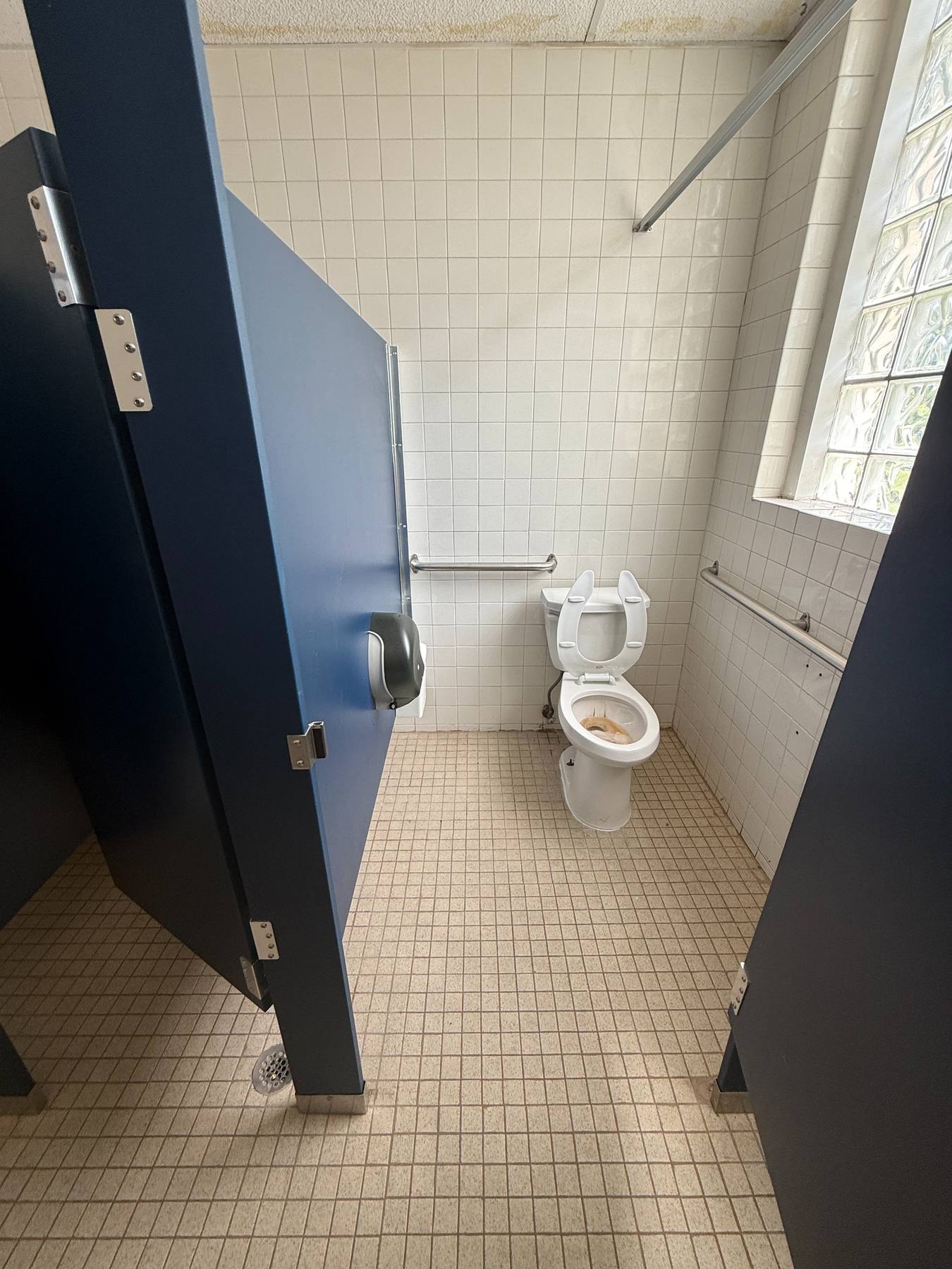 An outdated interior restroom with worn fixtures and dated tile.